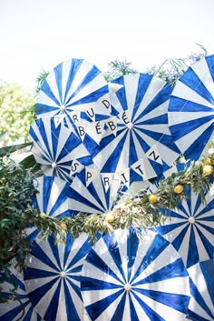 several blue and white umbrellas with words written on them are hanging from a tree