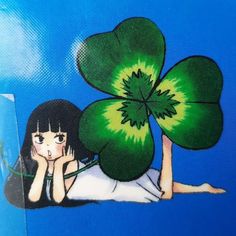 a woman laying on the ground with a four leaf clover in her hand and another drawing behind her