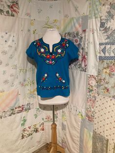 "Embroidered turquoise blouse. 100% manta (raw cotton). no stretch. M. SEE MEASUREMENTS BELOW.  Well made in great condition.  Sleeve length from neck opening 8.5\" Bust 42\" Hips 42\" Length from center back 23\" Dress Form is 36-26-37 My home is smoke free. Clothing is measured while laying flat and unstretched. I highly recommend taking the time to measure something that fits you well for comparison. Remember that you need breathing room that is not included in the measurements.  Any flaws ar Light Blue Short Sleeve Top With Floral Embroidery, Light Blue Embroidered Cotton Shirt, Light Blue Cotton Embroidered Shirt, Fitted Cotton Embroidered Top With Crew Neck, Blue Cotton Shirt With Floral Embroidery, Blue Floral Embroidered Crew Neck Top, Blue Crew Neck Top With Floral Embroidery, Blue Cotton Top With Floral Embroidery, Blue Cotton Bohemian Tops