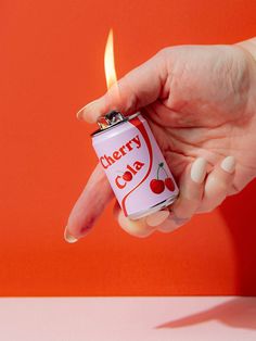 a person holding a lighter in their hand with the word cherry cola written on it