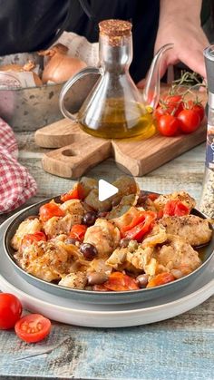 a plate full of food sitting on a table with tomatoes and olives next to it