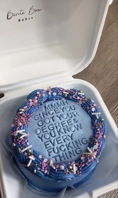 a blue cake with white frosting and pink sprinkles on it in a box