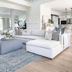 a living room filled with white furniture and lots of pillows on top of a rug