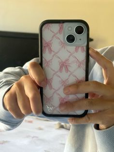 a woman holding up her phone case with pink flowers on it