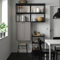 a kitchen with white cabinets and black chairs next to a dining room table in front of a window