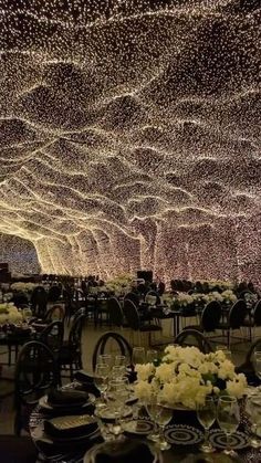 a large room filled with lots of tables covered in white flowers and lit up lights