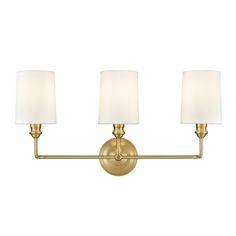 three light bathroom fixture with white shades on the wall and gold finish, in an antique style