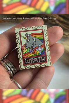 a hand holding a small wooden pin with an image of a unicorn on it's back