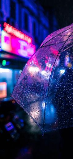 a person holding an umbrella on a city street at night with neon signs in the background