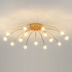 a chandelier with stars hanging from it's ceiling and the lights turned on