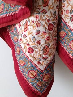 a red and white pillow sitting on top of a wooden table next to a wall