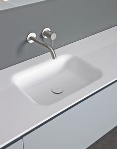 a white sink sitting on top of a counter next to a wall mounted faucet