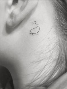 a woman's ear with a small cat tattoo on it