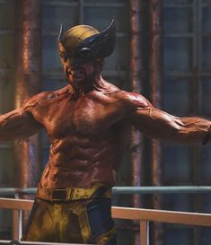 a man dressed as wolverine stands in front of a metal fence with his arms outstretched