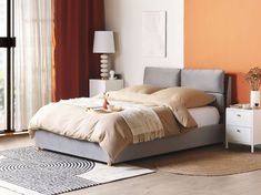 a bedroom with an orange wall and white furniture in the room, including a bed