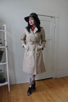 "This original Burberry London Trench is in great condition. It is a longer overcoat that hits just below the knee for more warmth and an overall mysterious look. Perfect for early spring, light fall or a mild winter.  The quality of this coat and the detailing says that is it from the 70's or early 80's. Overall in great condition with all buttons, and belt intact.  To compare, Sam is 5'4\" and measures as an average Medium or Size 6. Please let us know if you have any questions on fit! DETAILS Knee Length Burberry Trench Coat Color | Tan Material | Cotton, Polyester Made | London, England Size | Size 10 or Large Condition | Excellent" Retro Spring Workwear Outerwear, Spring Full-length Workwear Outerwear, Spring Full Length Outerwear For Work, Spring Full-length Outerwear For Work, Vintage Spring Workwear Outerwear, Vintage Spring Outerwear For Work, Vintage Outerwear For Spring Workwear, Trench Outfit, Trench Coat Vintage