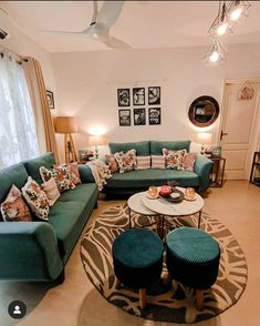 a living room filled with lots of green couches and pillows on top of a rug