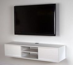 a flat screen tv mounted on the wall above a white entertainment center in a living room