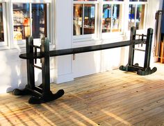 a black bench sitting on top of a wooden floor next to a store front window