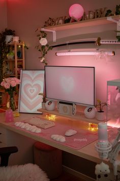 two computer monitors sitting on top of a desk next to pink flowers and other decorations