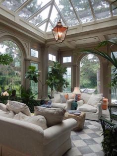 a living room filled with white furniture and lots of windows on top of each other