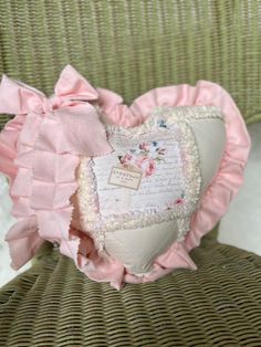 a heart shaped pillow sitting on top of a chair with pink ruffles and bows