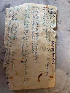 an old piece of paper with writing on it sitting on a counter top next to a cell phone