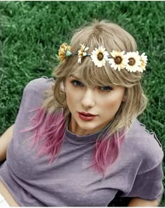 a woman with pink hair and sunflowers on her head sitting in the grass