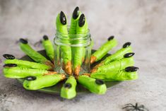 green fake nails with black tips are arranged on a plate next to a small jar