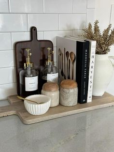 some bottles and spoons sitting on a shelf in a kitchen next to a book