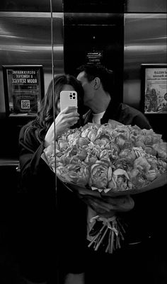 a man holding a bouquet of flowers taking a selfie with his cell phone in front of him