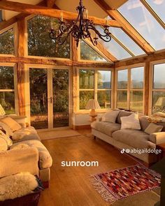 a living room with couches and windows overlooking the countryside in the evening sun light