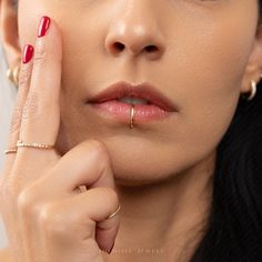 a close up of a person with a ring on her finger and red nail polish