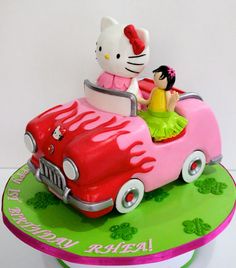 a hello kitty car cake with a girl in the driver's seat on top