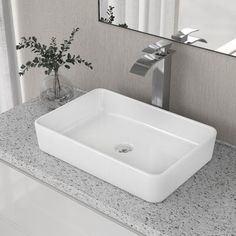 a white square sink sitting on top of a counter next to a vase with flowers