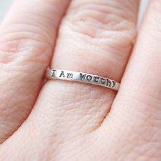 Skinny sterling silver ring that measures 2mm wide stamped with I am Worthy. Ring can come in sizes 4, 5, 6, 7, 8, 9, and 10. *Due to the process of hand stamping in each letter, the ring can stretch to be up to 1/2 size larger. Not sure of your ring size? Head over to this free printable to find your size. https://www.jewelry-secrets.com/Blog/wp-content/uploads/2015/05/Ring-Size-Chart1.pdf All Simpli Stamped jewelry comes ready to gift, packaged in a charming kraft box, tied with a coordinating Inspirational Stackable Jewelry As A Gift, Inspirational Stackable Jewelry As Gift, Inspirational Promise Jewelry, Meaningful Hypoallergenic Jewelry For Promise, Meaningful Hypoallergenic Promise Jewelry, Hypoallergenic Meaningful Jewelry For Promises, Meaningful Stamped Jewelry For Promise, Inspirational Engraved Jewelry For Anniversary, Inspirational Engraved Text Jewelry For Anniversary