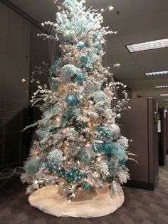 a decorated christmas tree in an office cubicle with blue and silver ornaments on it