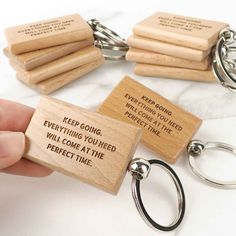 wooden keychain with engraved message on the front and back, which is being held by a person's hand