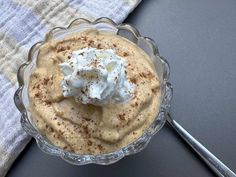 a bowl filled with whipped cream sitting on top of a table next to a spoon