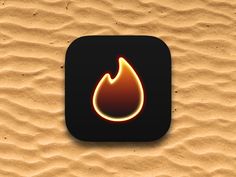 a black square button with a yellow flame on it's side in the sand