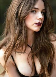 a woman with long brown hair wearing a black bra and red lipstick on her lips