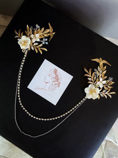 two brooches with flowers and chains attached to them on top of a table