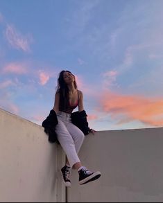 a woman sitting on the side of a wall with her feet up in the air