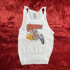 "Ribbed tank with a CHOPPERS handpressed graphic inspired by 70's & 80's bikers. All tanks will have a cut hem. If you want it extra shredded, let us know and we'll add holes, tears, wear marks etc... Want it cropped? Leave us a note! Available in white, unisex xs-xxl. Chest Measurements : XS (boys XL) - 32\"- 34\" S - 34\"- 36\" M - 38\" - 40\" L - 42\" - 44\" XL - 46\" - 48\" XXL - 50\" - 52\" Stay up to date on new items by following us on Instagram: @shophothoney ------ Imperfections &am Y2k Graphic Print Racerback Top, Y2k Racerback Top With Graphic Print, Retro White Tank Top For Streetwear, Vintage Tank Top For Spring Streetwear, Retro Graphic Print Tank Top, Retro Graphic Print Tank Top For Streetwear, Retro Racerback Tank Top With Graphic Print, Grunge Cotton Tops For Biker Events, Vintage Tank Top For Streetwear