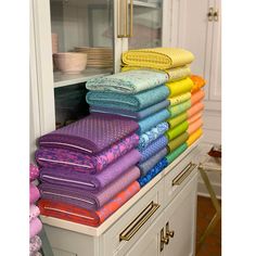 a stack of folded towels sitting on top of a white cabinet next to a pile of stuffed animals