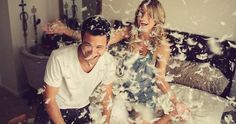 a man and woman sitting on top of a bed covered in confetti