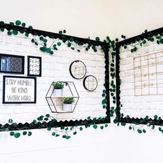 a white brick wall with green plants and pictures on it