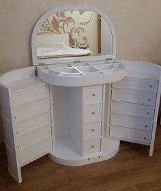 a white vanity with drawers and a mirror on the wall next to wooden flooring