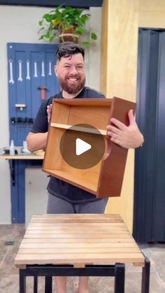 a man holding up a box on top of a wooden table