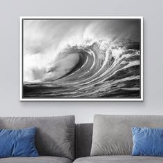 a black and white photo of a wave in the ocean on a wall above a couch